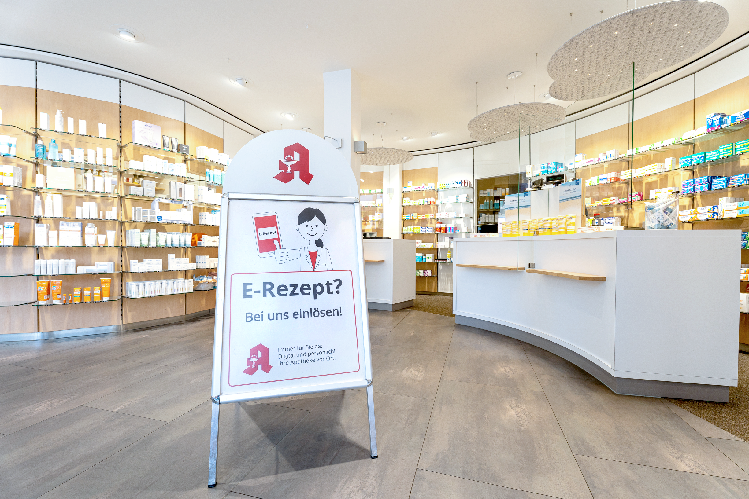 Einblick in die Apotheke am Ochsenmarkt: beleuchtete Regale und weiße Theke